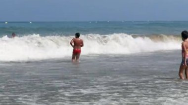 Birçok çocuk sahilde birlikte yüzüyor.