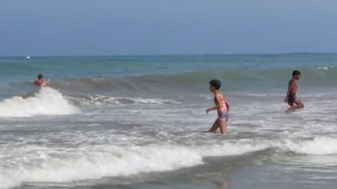 Birçok çocuk sahilde birlikte yüzüyor.