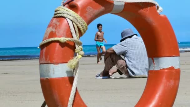 Samotny Mężczyzna Siedzący Samotnie Plaży Oprawiony Pomarańczowy Pierścień Ratunkowy — Wideo stockowe