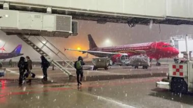 Brüksel 'de bir uçak park halindeyken bir kaç yolcu bir uçağın merdivenine doğru yürüyordu.