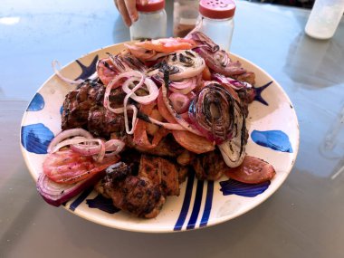 Bir tabak biftek kebabı. Dilimli, soğanlı ve domatesli.