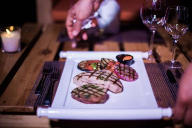 Bir tabak ızgara tavuk göğsü. Izgara patates, domates ve soğan.