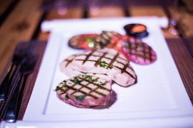 Bir tabak ızgara tavuk göğsü. Izgara patates, domates ve soğan.