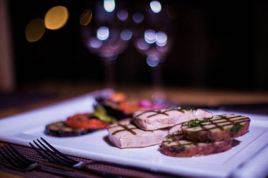 Bir tabak ızgara tavuk göğsü. Izgara patates, domates ve soğan.