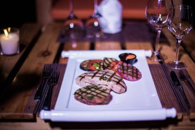 Bir tabak ızgara tavuk göğsü. Izgara patates, domates ve soğan.