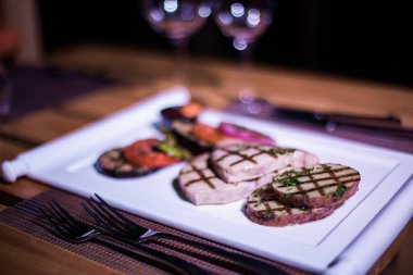 Bir tabak ızgara tavuk göğsü. Izgara patates, domates ve soğan.