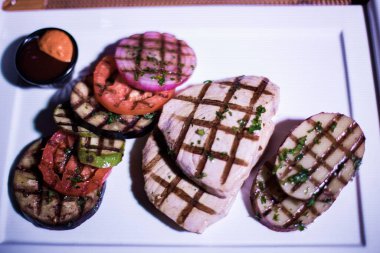 Bir tabak ızgara tavuk göğsü. Izgara patates, domates ve soğan.