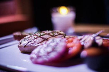 Bir tabak ızgara tavuk göğsü. Izgara patates, domates ve soğan.