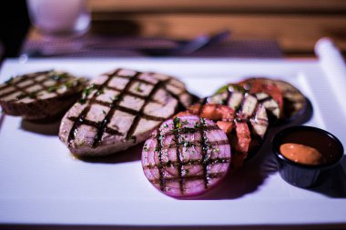 Bir tabak ızgara tavuk göğsü. Izgara patates, domates ve soğan.