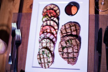 Kızarmış patates, domates ve soğanlı bir tabak et.