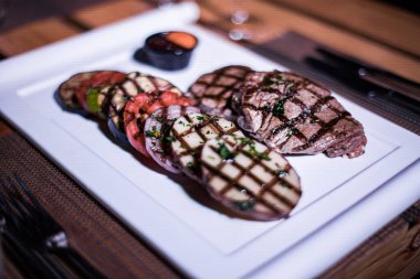 Kızarmış patates, domates ve soğanlı bir tabak et.