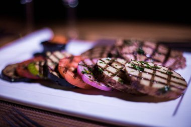 Kızarmış patates, domates ve soğanlı bir tabak et.