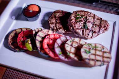 Kızarmış patates, domates ve soğanlı bir tabak et.