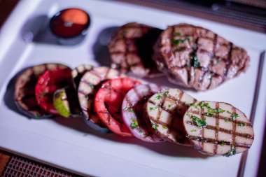 Kızarmış patates, domates ve soğanlı bir tabak et.