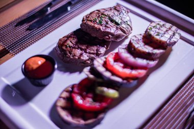 Kızarmış patates, domates ve soğanlı bir tabak et.