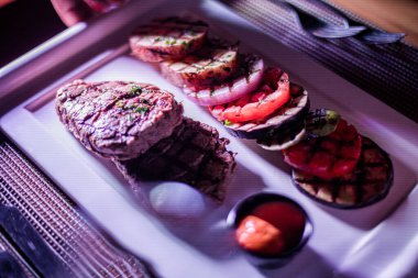 Kızarmış patates, domates ve soğanlı bir tabak et.