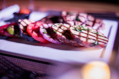 Kızarmış patates, domates ve soğanlı bir tabak et.