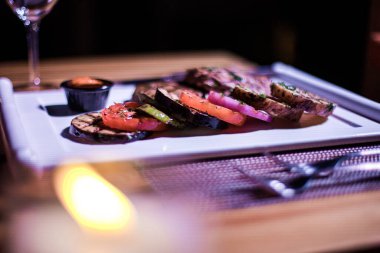 Kızarmış patates, domates ve soğanlı bir tabak et.