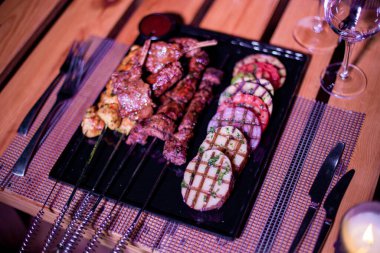 Izgara domates, patates ve soğanlı bir tabak tavuk ve biftek. 