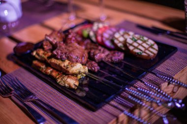 Izgara domates, patates ve soğanlı bir tabak tavuk ve biftek. 