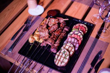 Izgara domates, patates ve soğanlı bir tabak tavuk ve biftek. 