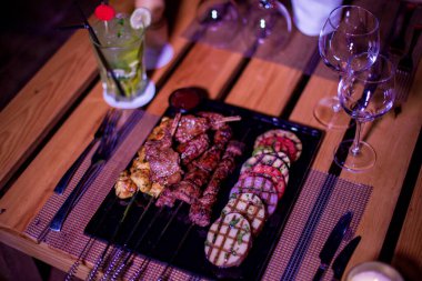 Izgara domates, patates ve soğanlı bir tabak tavuk ve biftek. 