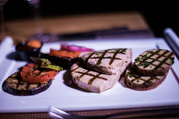 Bir tabak ızgara tavuk göğsü. Izgara patates, domates ve soğan.