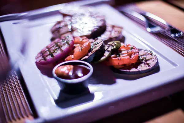 Bir tabak ızgara tavuk göğsü. Izgara patates, domates ve soğan.