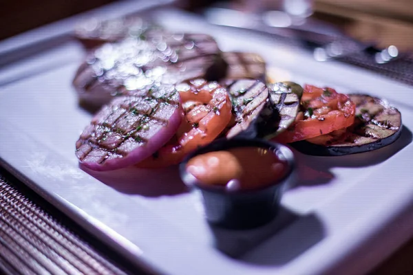 Bir tabak ızgara tavuk göğsü. Izgara patates, domates ve soğan.