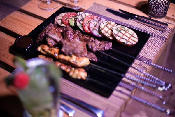 Izgara domates, patates ve soğanlı bir tabak tavuk ve biftek. 