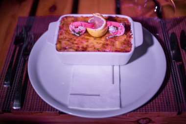 Masadaki parlak tencerede deniz ürünleri lazanyası.