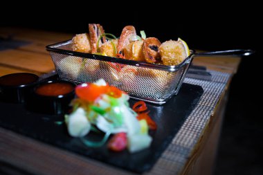 Yanında küçük bir salata porsiyonu olan metal bir kasede tavuk külçeleri.