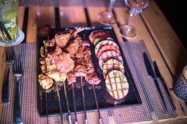 Izgara domates, patates ve soğanlı bir tabak tavuk ve biftek. 