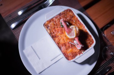 Masadaki parlak tencerede deniz ürünleri lazanyası.