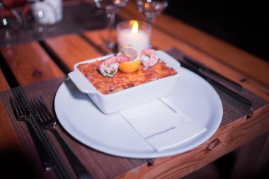 Masadaki parlak tencerede deniz ürünleri lazanyası.