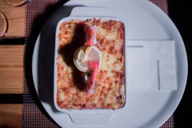 Masadaki parlak tencerede deniz ürünleri lazanyası.