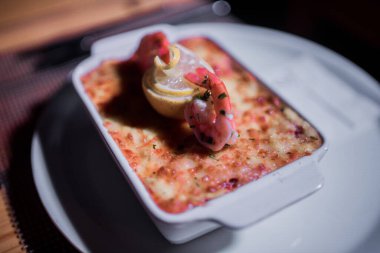 Masadaki parlak tencerede deniz ürünleri lazanyası.