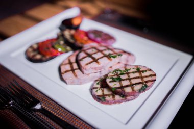 Bir tabak ızgara tavuk göğsü. Izgara patates, domates ve soğan.