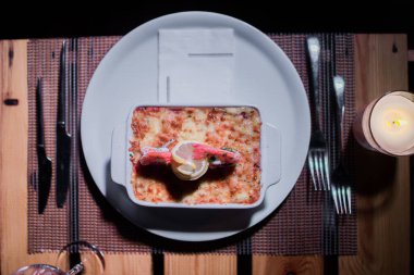 Masadaki parlak tencerede deniz ürünleri lazanyası.