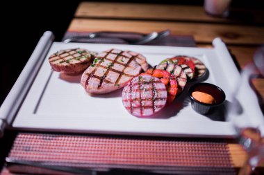 Bir tabak ızgara tavuk göğsü. Izgara patates, domates ve soğan.