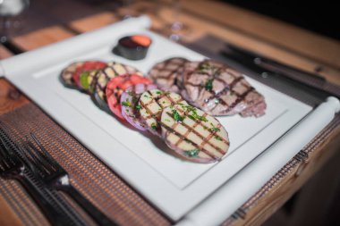 Kızarmış patates, domates ve soğanlı bir tabak et.