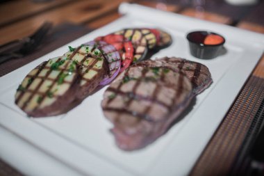 Kızarmış patates, domates ve soğanlı bir tabak et.