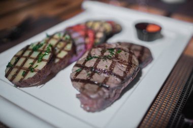 Kızarmış patates, domates ve soğanlı bir tabak et.