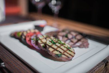 Kızarmış patates, domates ve soğanlı bir tabak et.