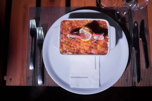 Masadaki parlak tencerede deniz ürünleri lazanyası.