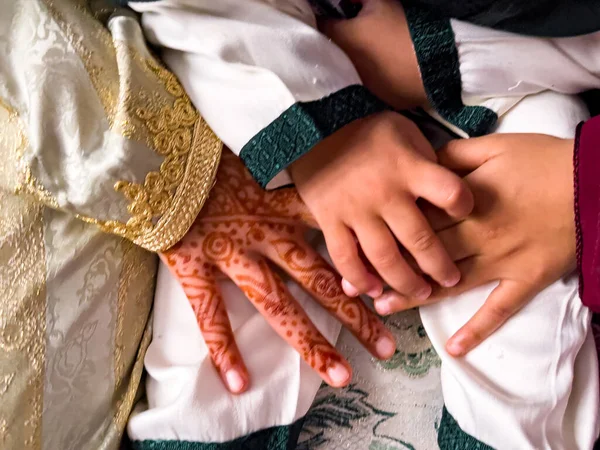 Henah dövmeli küçük bir kız müslüman töreninde bir çocuğun elini tutuyor.