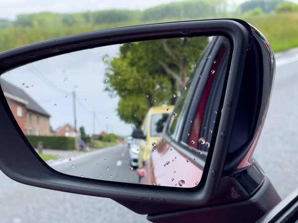Reflection of traffic flow on the side mirror of a red car