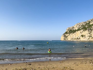 Bir grup insan sahilde yaz tatilinin tadını çıkarıyor.