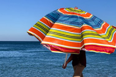 A man holding an open parasol on the beach