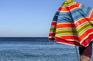 A man holding an open parasol on the beach